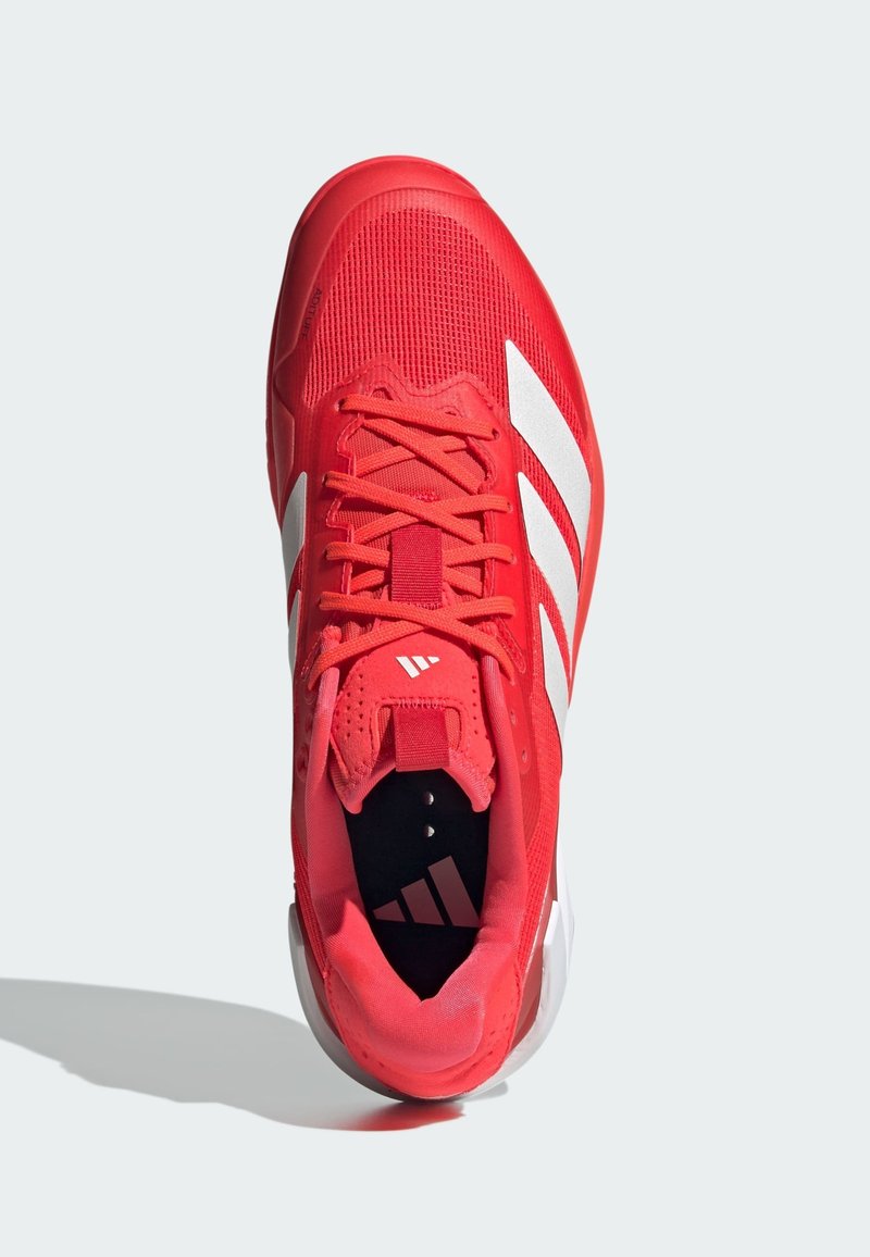 Chaussure de sport rouge avec empeigne en mesh, rayures blanches accentuées et lacets. Elle dispose d'un col rembourré et d'une semelle intérieure à motifs avec logo.