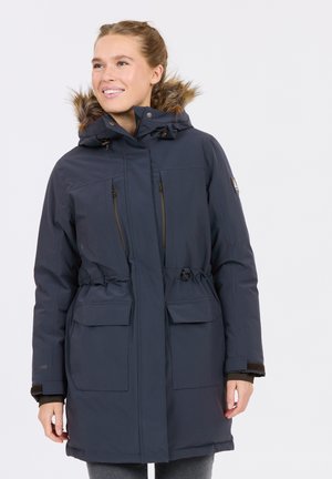 Marinblå parka med huva i fuskpäls, frontal dragkedja, justerbar midja och två stora framfickor. Har en mjuk textur.