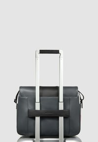 Grijze leren tas met een zwarte acccent, bevestigd aan een zilveren handvat van bagage, met een klep-sluiting en zijden trekkoorddetail.