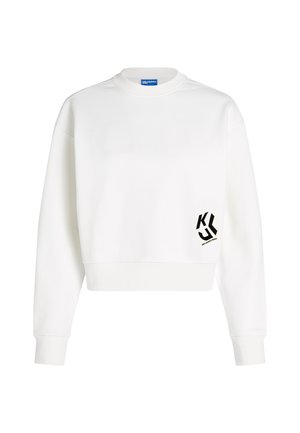 Bela dolgodlaka majica s črnim stiliziranim logotipom "KL" in majhnim besedilom na spodnjem desnem sprednjem delu.