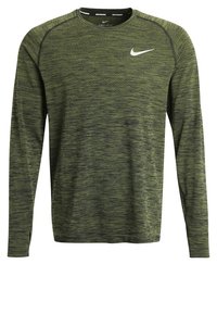 Långärmad grön träningströja i texturerad tyg med ett subtilt mönster, med en vit Nike-logotyp på vänster bröst och rund halsringning.