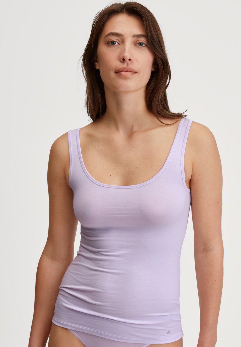 Lilac tank top with a scoop neckline and wide straps, made of soft, stretchy fabric, featuring a fitted silhouette and smooth texture.
