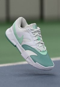 Nike sneakers med en hvid mesh-overdel og teal-detaljer. Har en glat tåboks, struktureret sidepanel og mønstret sål.
