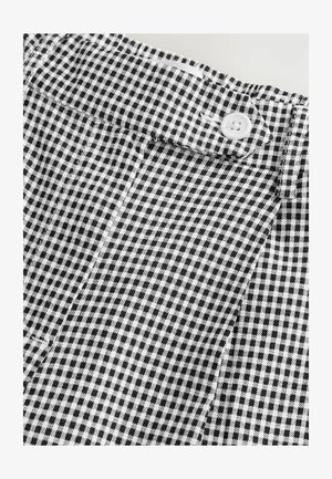 Sort-hvidt gingham-mønster stof med knaplukning og tekstureret vævning, der viser et skarpt, ternet design.