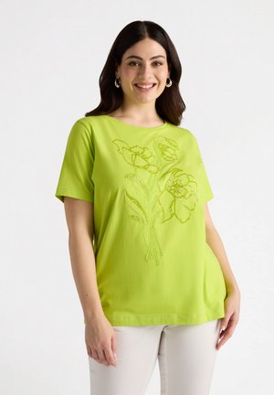 Haut à manches courtes vert citron en tissu doux, orné d'une broderie florale dans un design tonal. Coupe décontractée avec un col rond.