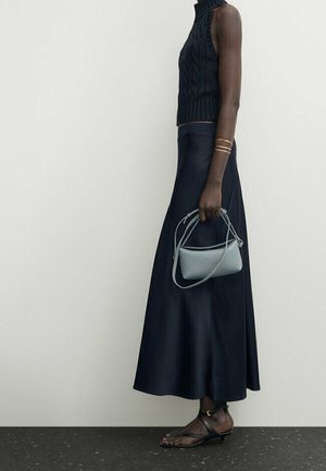 Haut sans manches en maille bleu marine, col montant ; jupe longue fluide bleu marine ; sac à main arrondi bleu clair ; sandales noires à fines lanières ; design minimaliste.