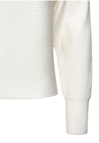 Weißer gerippter Pullover aus strukturiertem Stoff, mit lockerem Schnitt und langen Ärmeln. Die Bündchen sind enganliegend und betonen die Gesamtform.