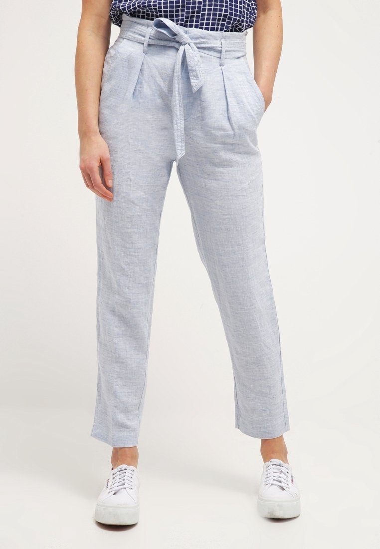 Ljusblå linbyxor med knytmidja, veck framtill, smala ben och sidfickor, som bärs med vita sneakers.