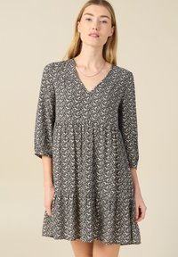 Vestido de estampado floral en blanco y negro con escote en V, mangas 3/4 y falda con fruncidos. Tejido ligero con una silueta fluida.
