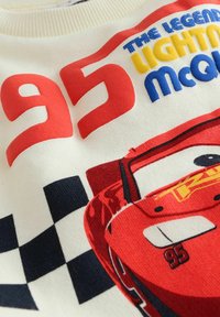 Sudadera blanca con un gran '95' rojo y gráficos coloridos que presentan un coche de carreras rojo y un patrón de cuadros. Textura de algodón suave.