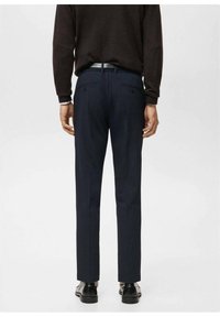 Granatowe, dopasowane spodnie garniturowe o smukłym kroju, wykonane z gładkiej tkaniny, z dwoma tylnymi kieszeniami i subtelnym połyskiem, zestawione z czarnymi butami.