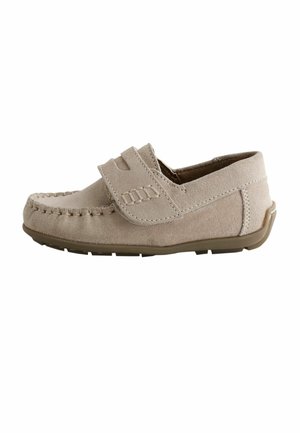 Beige suède kinderslof met gestikte mocassin neus en verstelbare klittenbandsluiting op een bruine rubberen zool.
