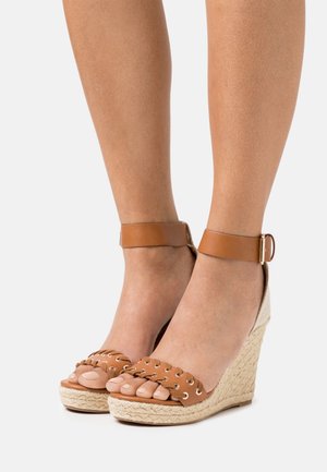 Brune læder wedge sandaler med ankelrem, vævet jute platform og dekorative huller på tåremmen.