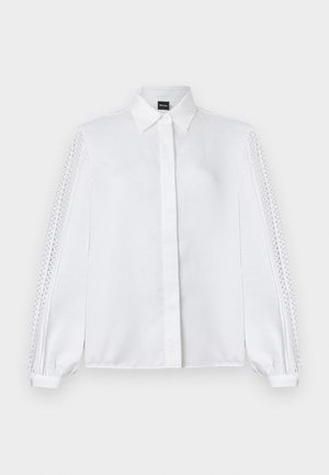 Bijela bluza s dugim rukavima s oštrim ovratnikom i čipkastim detaljima koji se protežu duž rukava, manžete s gumbima i skriveni prednji gumbi.