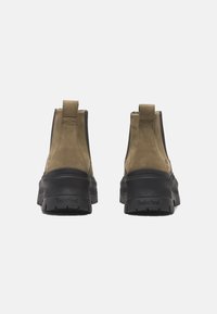 Bruna mocka ank stövlar med en svart gummisula och texturerat grepp. Har en dragflik bak och subtil branding på hälen.