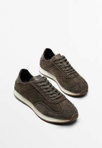 Pair of dark brown suede lace-up sneakers with white soles angled to the right on a plain light background.