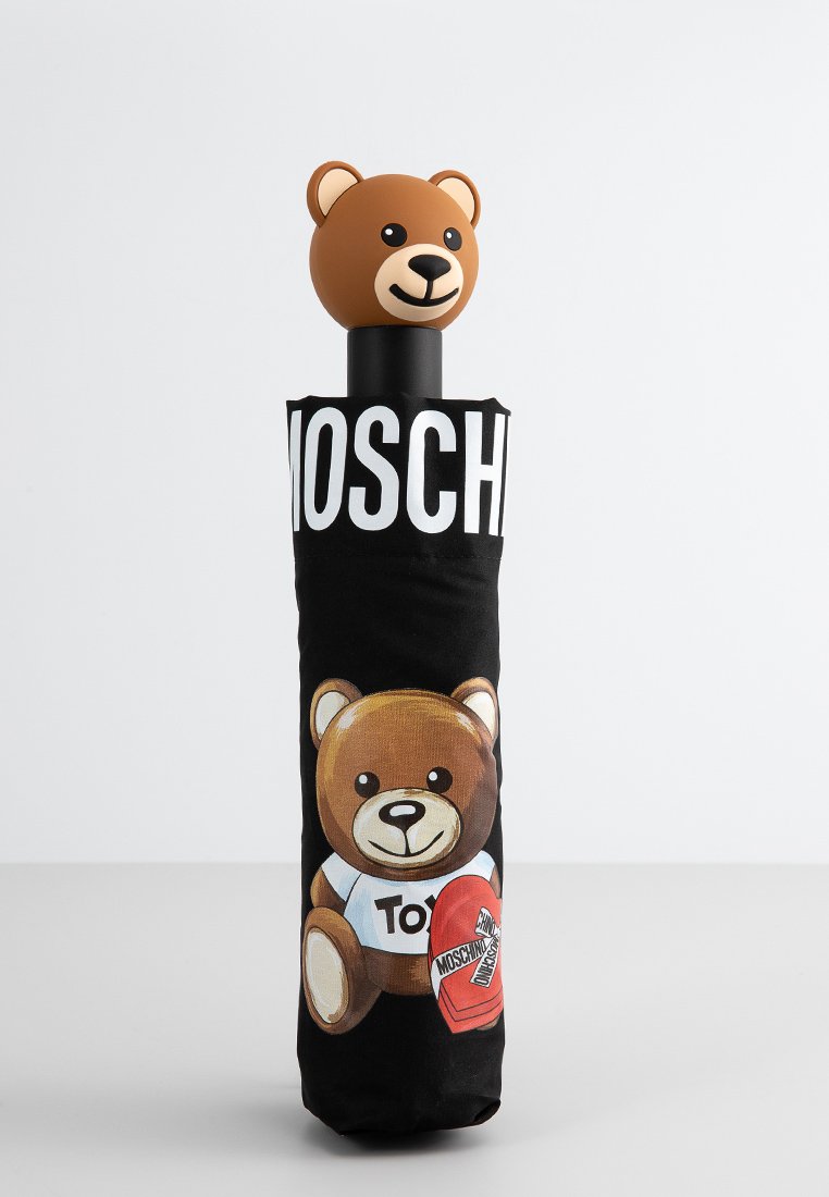 Parapluie noir avec une poignée en forme d'ours en peluche et un graphisme ludique d'ours. Présente le logo "MOSCHINO" sur le mât ; matériau en caoutchouc souple.