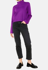 Suéter de cuello vuelto púrpura con mangas largas, combinado con jeans negros de tiro alto y mocasines negros de charol. Textura suave, corte relajado.
