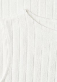 Tissu blanc côtelé avec un détail de col asymétrique, montrant la texture et un motif de rayures verticales.