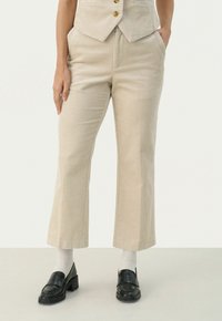 Beige corduroy broek met een flared pasvorm, gestreepte textuur in verticale lijnen, zijzakken en een middelhoge taille. Gecombineerd met zwarte instappers en witte sokken.
