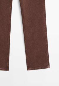 Jambes de pantalon en denim marron coupe droite montrées de mi-cuisse à l'ourlet sur fond blanc.
