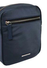 Borsa a tracolla in nylon blu navy con una cerniera argento, etichetta con logo e design elegante. Caratterizzata da una tasca frontale con zip e superficie liscia.