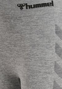 Grå atletiska shorts med en texturerad yta, prydda med en svart logotyp, ribbad midja och kontrasterande chevronmönstrade detaljer.