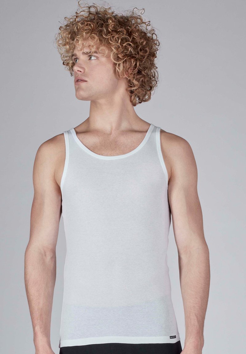 Light gray tank top with a fitted shape, made of soft cotton fabric. It features narrow straps and a contrasting trim around the neckline.