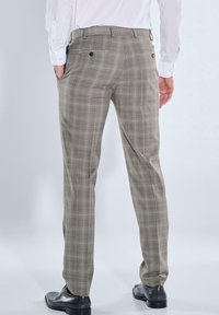 Beige karierte Hosen in maßgeschneiderter Passform mit flachen Vorderseiten, seitlichen und hinteren Taschen, kombiniert mit schwarzen Schuhen und einem weißen Hemd.