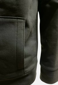 Felpa nera che mostra una vista laterale con una tasca, texture liscia e una vestibilità leggermente larga nella vita e nelle maniche.
