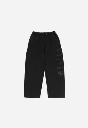 Pantalons de survêtement noirs avec une taille élastique et un cordon de serrage. Présentent des graphismes imprimés subtils en gris foncé sur la jambe gauche. Tissu doux et décontracté.
