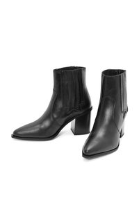 Botines de cuero negro con punta afilada, tacón grueso y acentos de panel vertical. Textura suave con un acabado pulido.