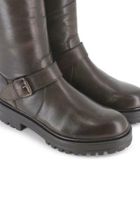 Botines de cuero marrón con puntera redondeada, detalle de correa y hebilla, y suela de goma negra texturizada. Acabado liso con brillo mínimo.