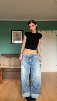 Φαρδιά ανοιχτόχρωμα τζιν παντελόνια με ξεθωριασμένο φινίρισμα, αναδιπλωμένα μπατζάκια και σχέδιο πέντε τσεπών, συνδυασμένα με ένα στενό μαύρο μπλουζάκι κοντό μανίκι.