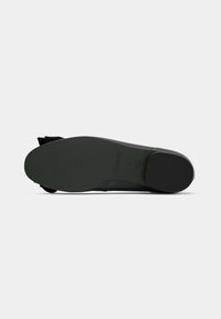 Semelle plate noire de chaussure vue par le dessous, lisse avec une légère texture, bout arrondi, petit talon bloc, nom de la marque "Gabor" et taille 5 visibles.