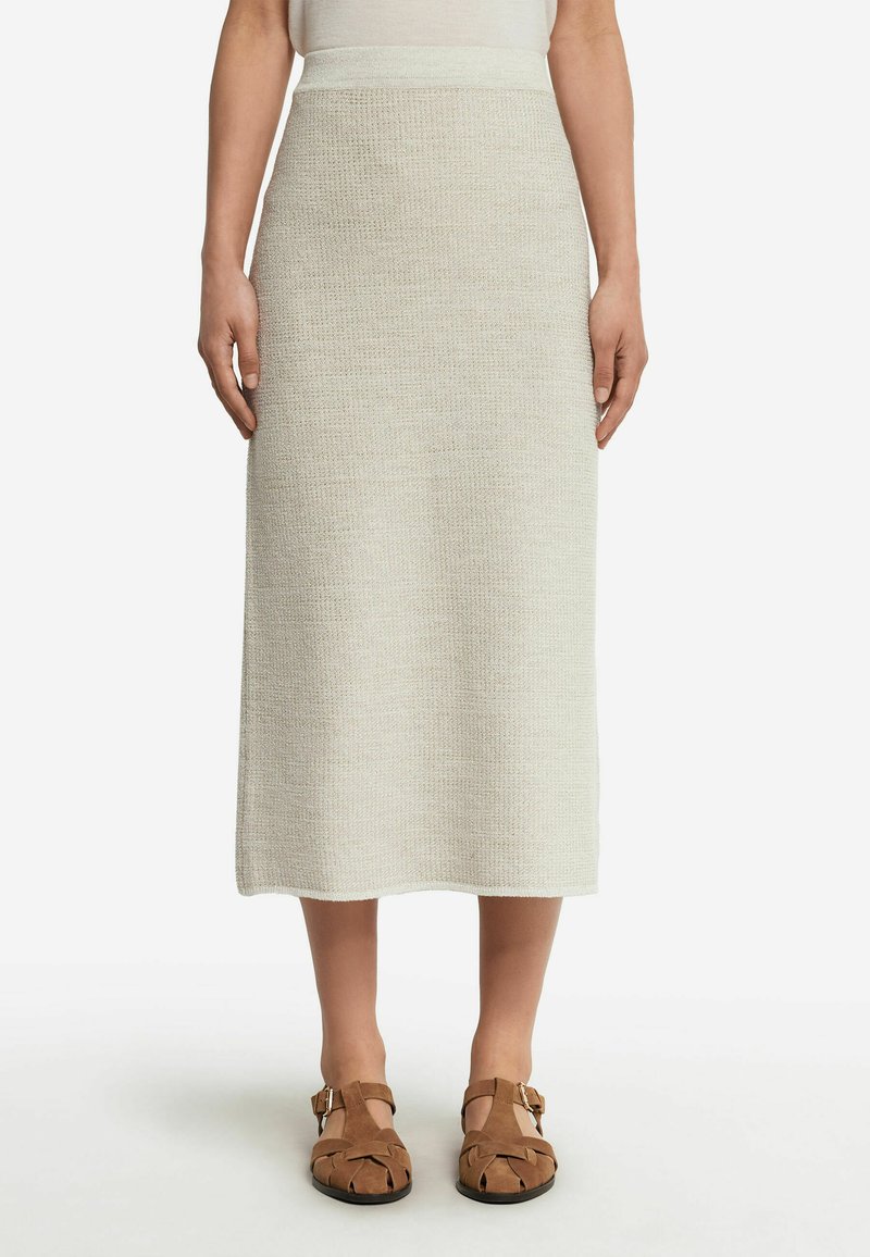 Stickad midiklänning i ljusbeige med ett strukturerat mönster, med en figursydd midja och en rak silhuett, i kombination med bruna sandaler.