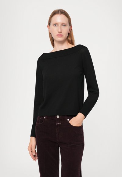Schwarzer Pullover mit weitem, schulterfreiem Ausschnitt, langen Ärmeln und glatter Textur, kombiniert mit dunkelburgunderfarbener Cordhose.