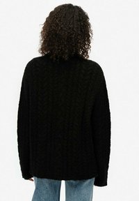 Czarny dziany sweter o fakturowanym wzorze, z luźnym krojem i wysokim dekoltem. Długie rękawy i miękki, puszysty materiał.