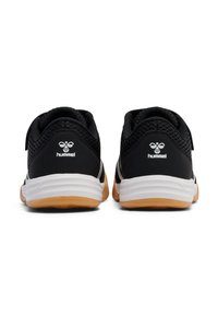 Chaussures de sport noires avec dessus en maille, semelle intermédiaire blanche et semelle extérieure en caoutchouc naturel. Comprend une sangle ajustable et un logo sur le talon.