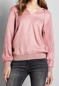 Rosa Satin-Hoodie mit V-Ausschnitt, langen Puffärmeln und elastischem Saum. Verfügt über einen Kordelzug an der Kapuze und eine glatte Textur.