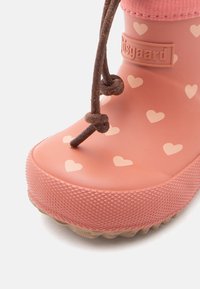 Stivale da pioggia in gomma rosa con piccoli cuori, con bordo elastico e dettagli in pizzo marrone. Superficie texturizzata con suola scanalata per una migliore aderenza.
