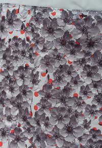 Diseño textil floral con flores grises y puntos rojos sobre un fondo blanco. Presenta una textura suave y patrones florales detallados.