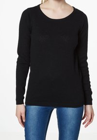 Jersey negro de manga larga con escote redondo y patrón de punto texturizado, con puños y dobladillo acanalados, combinado con jeans azules.