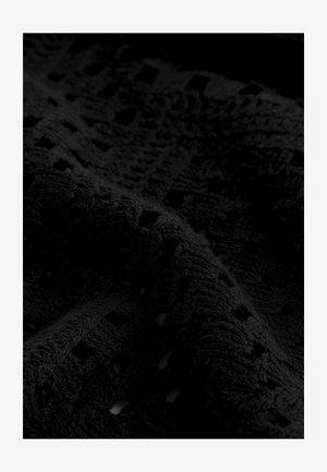Czarna teksturowana tkanina o pluszowej, przypominającej ręcznik powierzchni, z wzorem perforowanych kwadratów i poziomych linii.