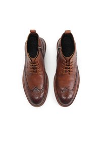 Bocanci din piele maro până la gleznă cu un model brogue, având fermoar, închidere cu șireturi și texturi contrastante. Bot ascuțit și talpă durabilă.