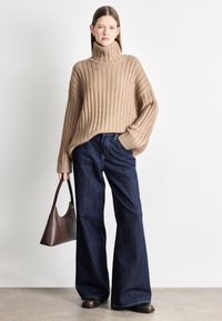 Ζιβάγκο πουλόβερ με ρίγες, φαρδιά γραμμή; σκούρο μπλε τζιν παντελόνι με φαρδιά μπατζάκια; καφέ δερμάτινη τσάντα χειρός; λεία υφή, καθημερινό στυλ.