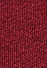 Primo piano di filato multicolore rosso e rosa lavorato a maglia in un motivo a coste verticali.