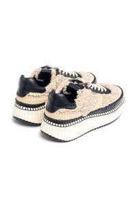 Beige und schwarze Plateau-Sneaker mit flauschigem Textil-Obermaterial, schwarzen Lederakzenten, dicker weißer Zwischensohle und dekorativer Naht.