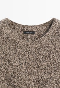 Maglione lavorato a maglia con motivo screziato grigio e beige. Presenta una scollatura rotonda e bordi a coste. Etichetta del marchio visibile all'interno del colletto.