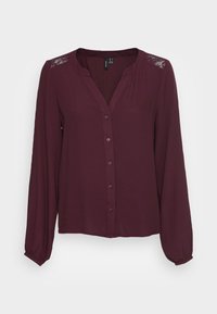 Blouse bordeaux boutonnée avec manches longues, encolure en V et détails en dentelle sur les épaules. Fabriquée en tissu doux avec une coupe décontractée.